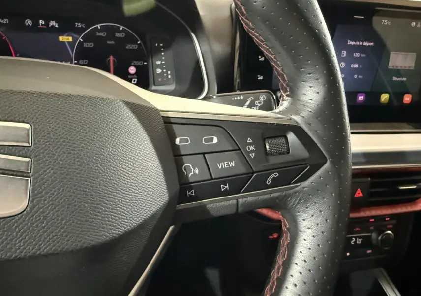 Gros plan sur le volant cuir et alu de la SEAT IBIZA 1.0 TSI 110 FR 2024, avec commandes multifonctions et tableau de bord numérique.