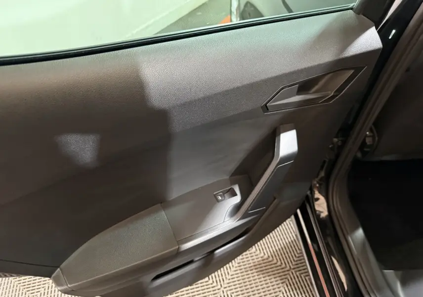 Vue rapprochée de la porte arrière droite noire d'une SEAT Ibiza 2024, avec poignée et commande de vitre électrique.