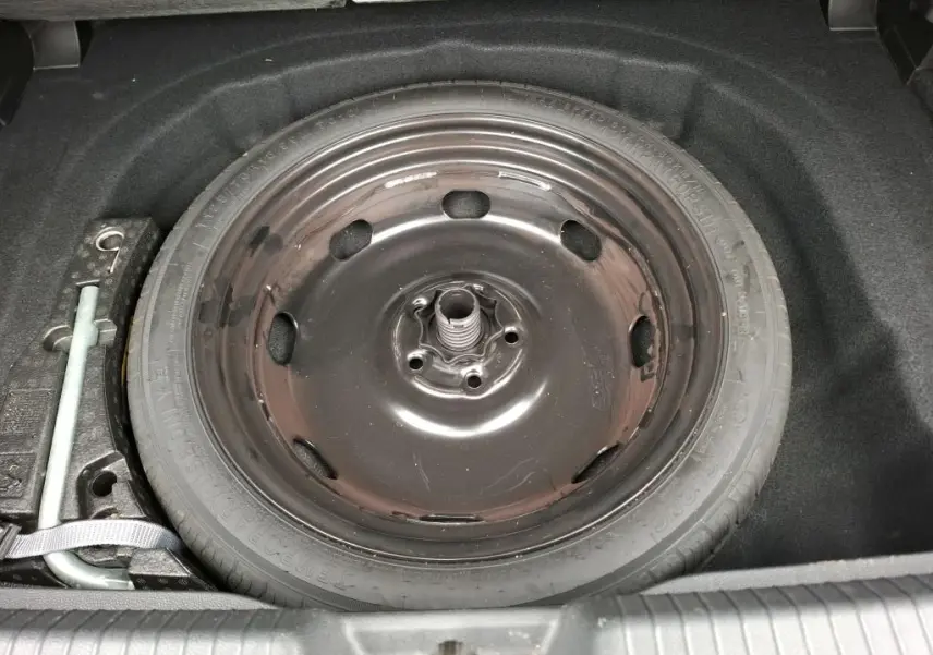 Vue rapprochée de la roue de secours noire dans le coffre d'une Volkswagen Golf 1.5 eTSI 130 DSG7 Active gris 2022.