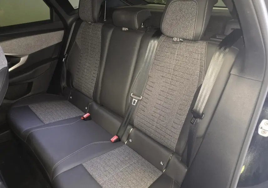 Vue intérieure côté gauche des sièges arrière gris tissu et noir cuir du Peugeot 3008 hybride 2025 avec ceintures de sécurité visibles.