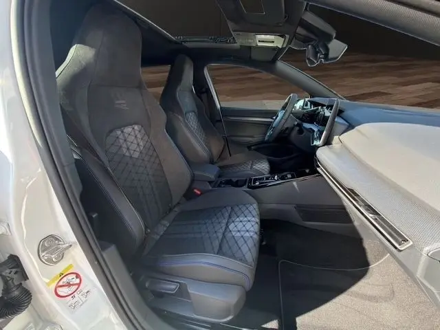 Vue intérieure côté conducteur de la Volkswagen Golf 2.0 TDI R-Line blanche, sièges sport et toit panoramique visibles.