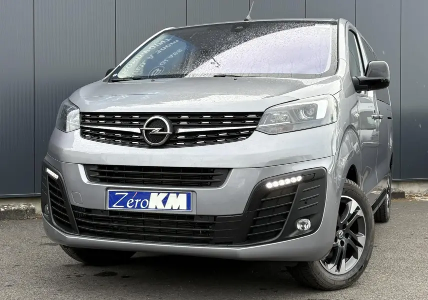 Vue 3/4 avant droit d'un Opel Zafira Life XL gris Artense avec calandre noire et feux LED allumés.