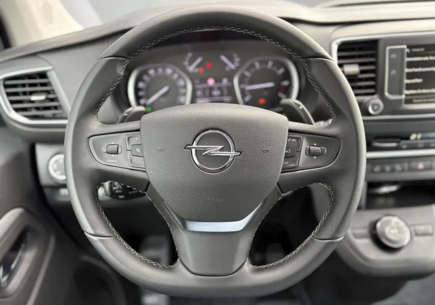 Volant en cuir noir avec logo Opel au centre, tableau de bord et écran tactile visibles en arrière-plan.
