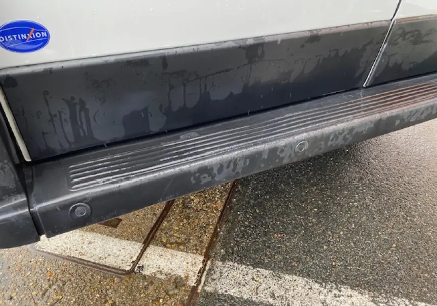 Gros plan sur la bas de caisse noir et la marche-pied d'un Opel Movano Fourgon blanc, côté droit, avec badge Distinxion.