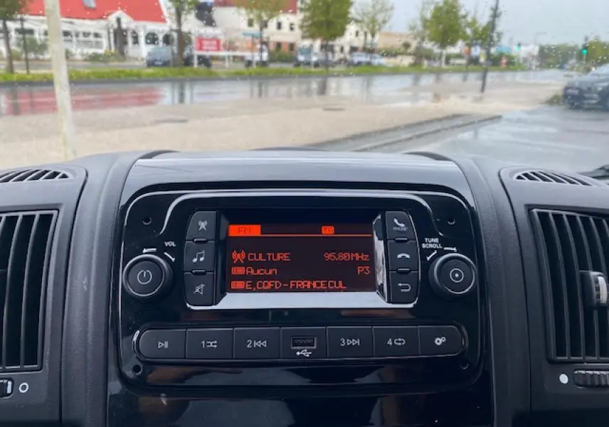 Vue rapprochée du tableau de bord noir de l'Opel Movano Fourgon 2023 avec radio affichant une station FM.