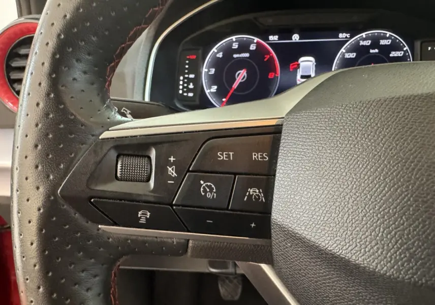 Gros plan sur le volant multifonctions en cuir perforé noir de la SEAT Ibiza 1.0 TSI 110 FR 2024, avec tableau de bord numérique.