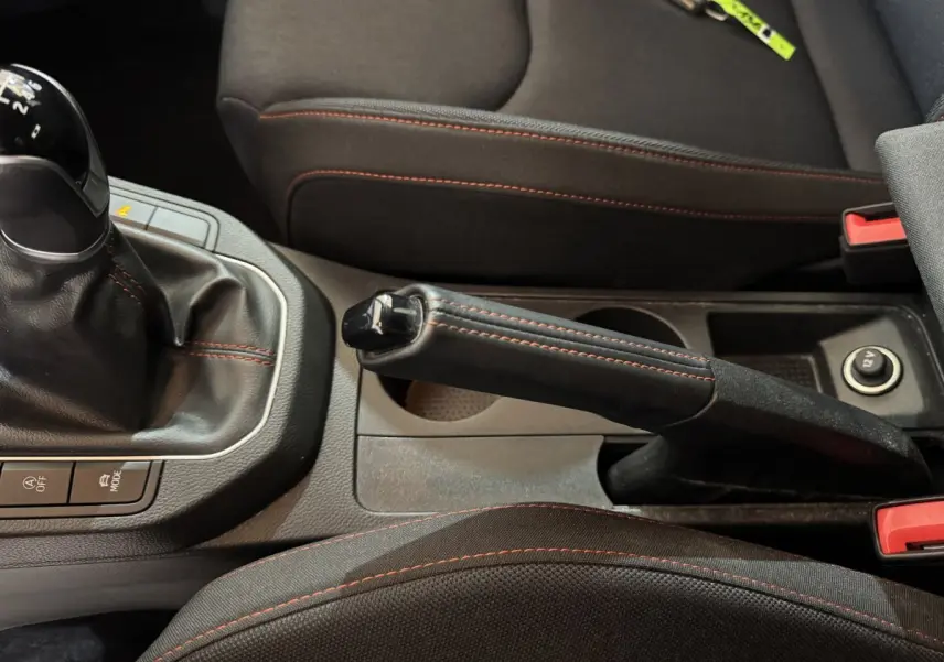 Gros plan intérieur sur frein à main et levier de vitesse manuelle avec surpiqûres rouges dans une SEAT Ibiza rouge 2024.