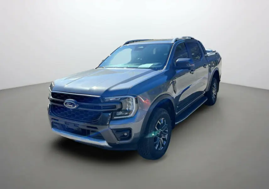 Ford Ranger 2026 gris carbone en 3/4 avant droit avec jantes alu 18 pouces et barres de toit visibles.
