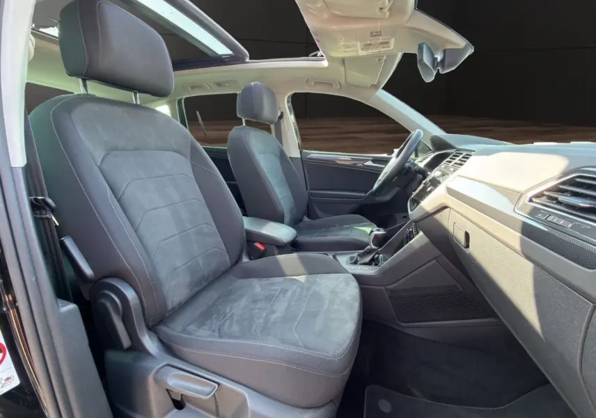 Vue intérieure côté droit du Volkswagen Tiguan noir 2022, sièges avant en tissu gris et toit ouvrant panoramique.