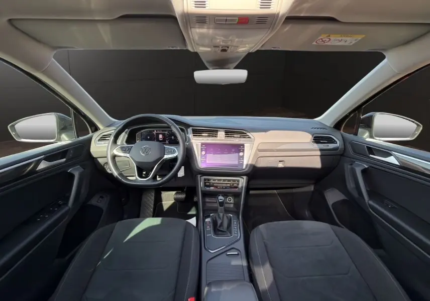 Vue intérieure avant du Volkswagen Tiguan noir 2022, tableau de bord avec écran tactile et volant multifonctions cuir.