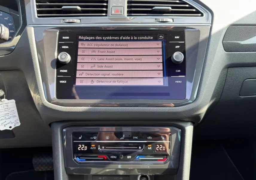 Vue rapprochée du tableau de bord noir du Volkswagen Tiguan 2022, avec écran tactile et commandes climatisation digitales.