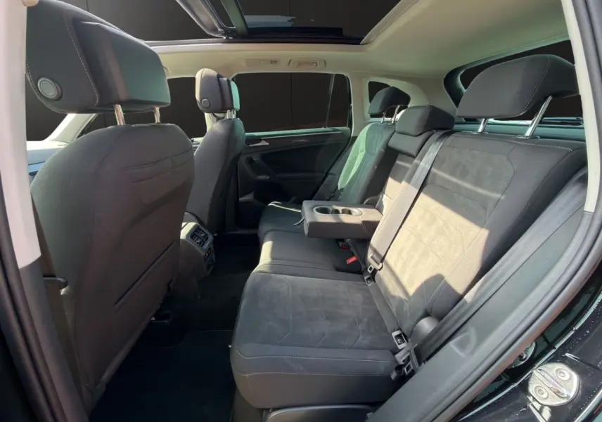Vue intérieure arrière côté droit du Volkswagen Tiguan noir 2022 avec banquette tissu et accoudoir central rabattable.
