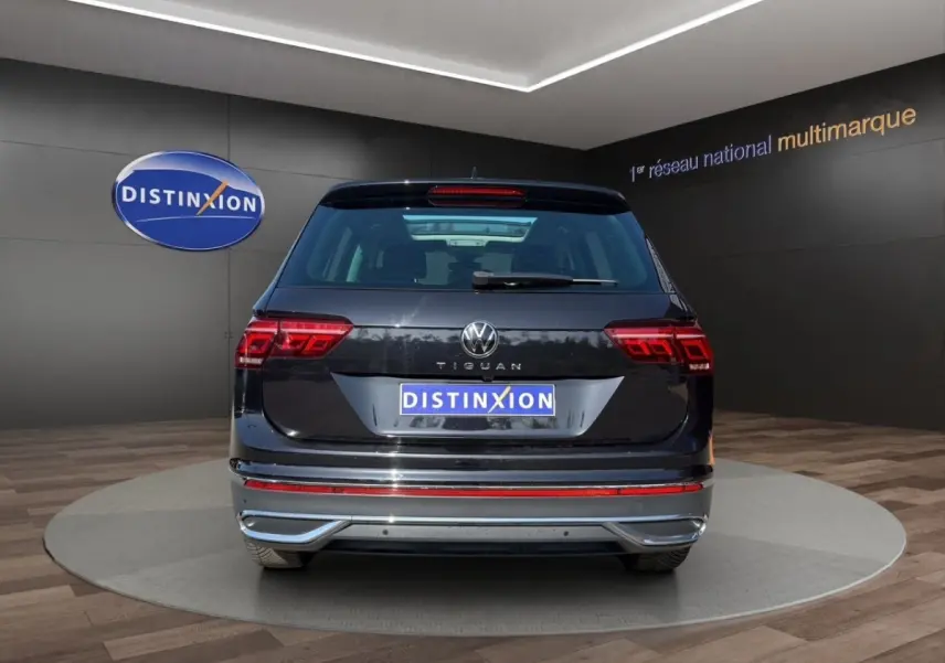 Vue arrière d'un Volkswagen Tiguan noir 2022 avec feux LED et logo distinctif sur fond de showroom.