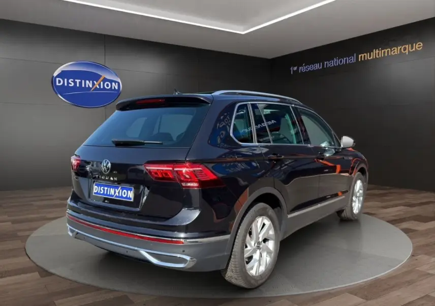 Volkswagen Tiguan noir vue 3/4 arrière droit en showroom avec jantes argentées et toit ouvrant.