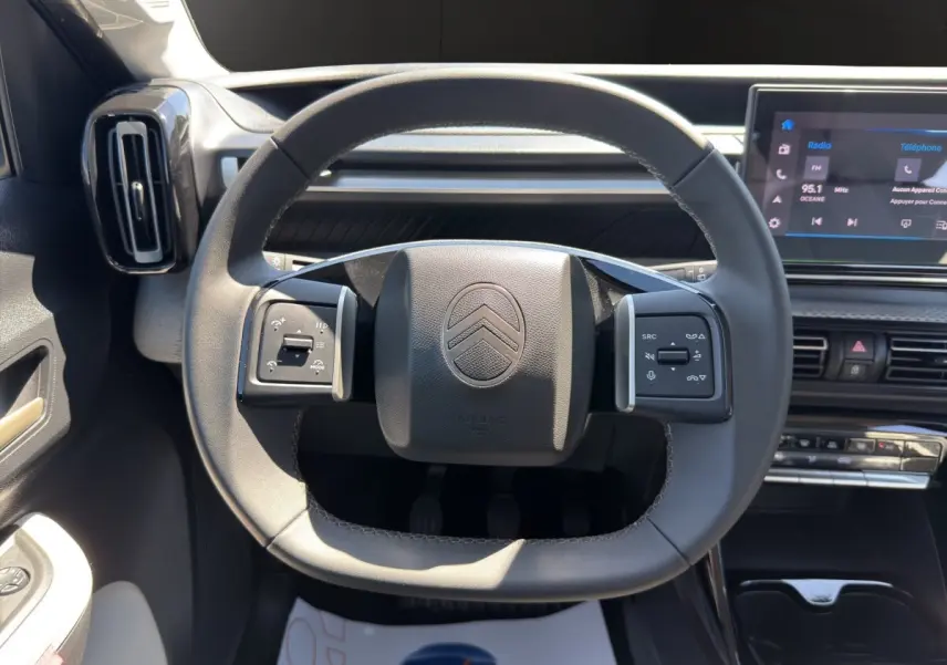 Vue rapprochée du volant cuir noir de la Citroën C3 Turbo 100 BVM6 MAX avec tableau de bord et écran tactile visible.