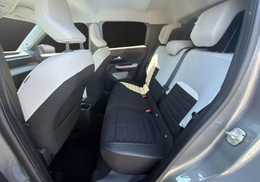 Vue intérieure arrière droite de la Citroën C3 2025 gris foncé, sièges bicolores noir et gris avec appuie-têtes intégrés.