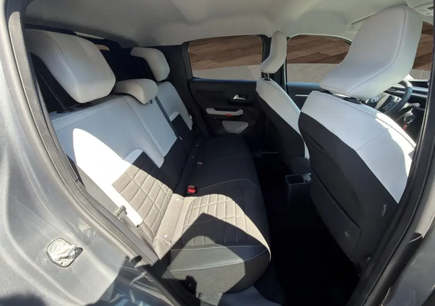 Vue intérieure arrière côté gauche de la Citroën C3 2025 gris foncé, sièges bi-ton noir et blanc avec appuie-têtes.