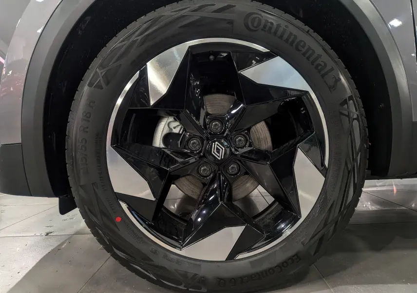 Gros plan sur la roue avant gauche du Renault Captur gris Cassiopé, avec jante noire et argentée au design étoilé.