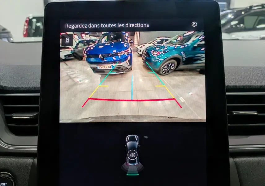 Écran de caméra de recul du Renault Captur gris Cassiopé montrant deux voitures garées en intérieur, vue arrière du véhicule.