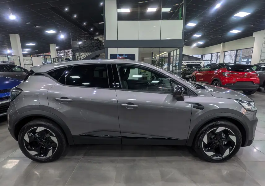 Profil côté gauche du Renault Captur 2025 gris Cassiopé avec jantes biton noires et grises en concession.