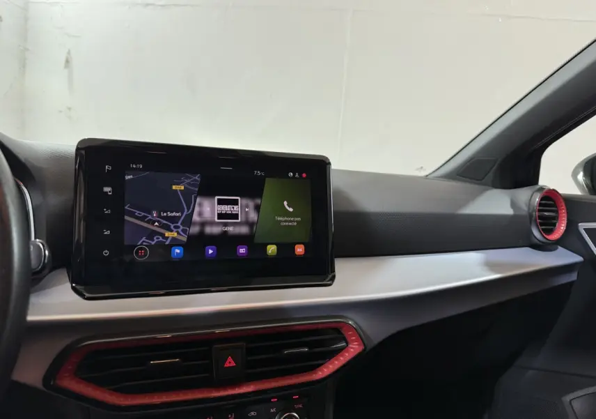 Vue intérieure du tableau de bord de la SEAT Ibiza 2024 noir, avec écran tactile central et aérateurs rouges.