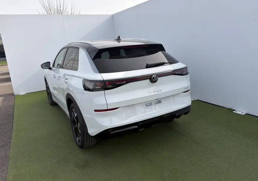 Vue 3/4 arrière droite du Volkswagen T-Roc blanc pur avec toit noir et feux arrière LED 3D sur fond neutre.