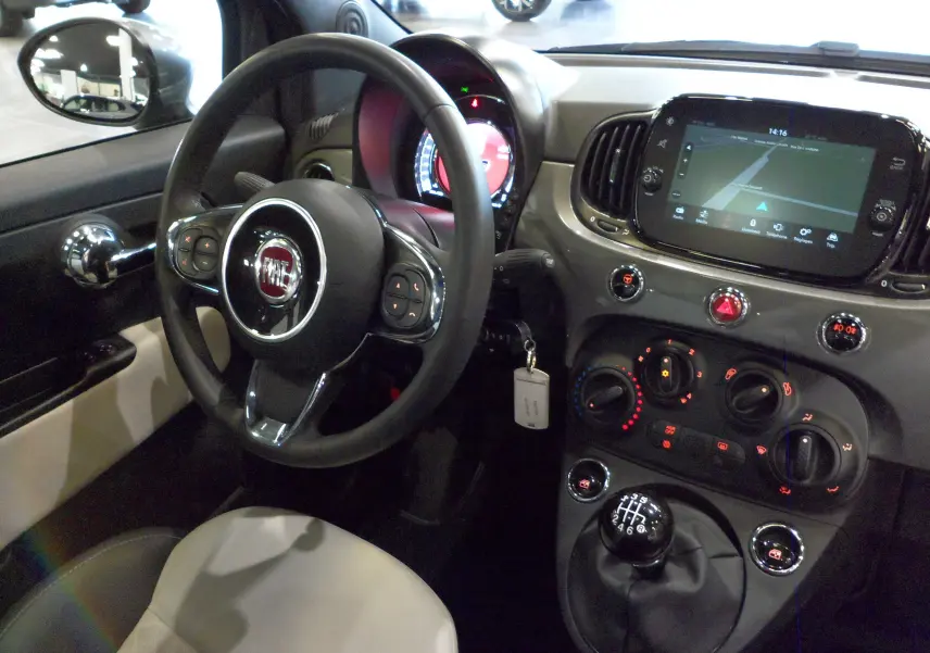 Vue intérieure côté conducteur de la Fiat 500 Electroclash Grey, avec volant multifonction et écran tactile central allumé.