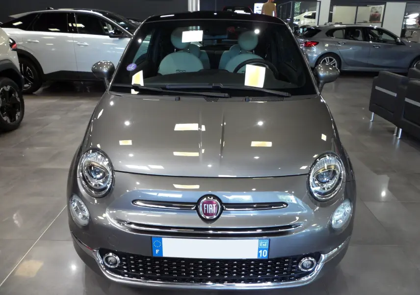 Vue frontale d'une FIAT 500 hybride 2021 en Electroclash Grey, avec phares ronds et calandre chromée brillante.