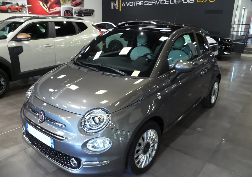 Vue 3/4 avant droite d'une Fiat 500 Electroclash Grey 2021 en hybride, avec jantes alliage et intérieur clair visible.