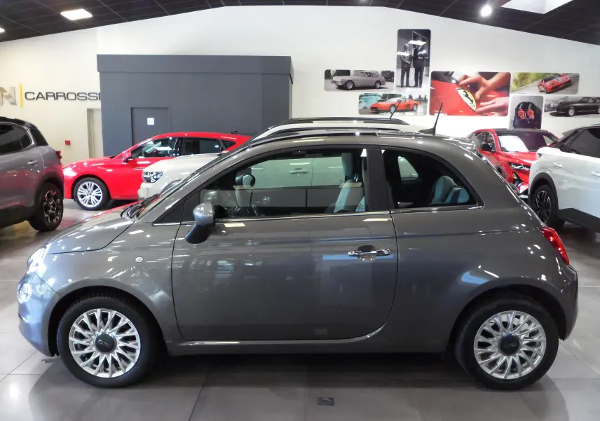 Profil côté gauche d'une FIAT 500 Electroclash Grey 2021 en hybride essence, avec toit ouvrant panoramique en showroom.