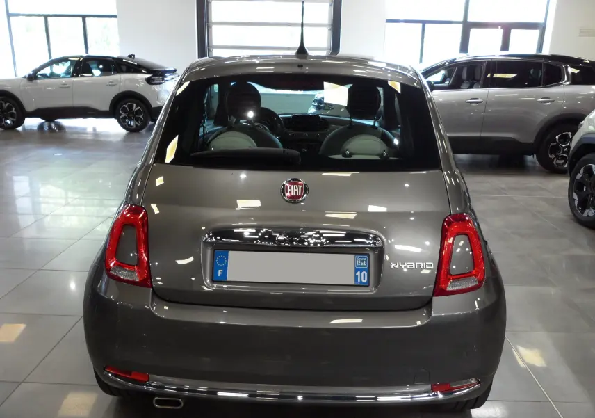 Vue arrière d'une Fiat 500 hybride Electroclash Grey exposée en showroom avec détails chromés et feux rouges.