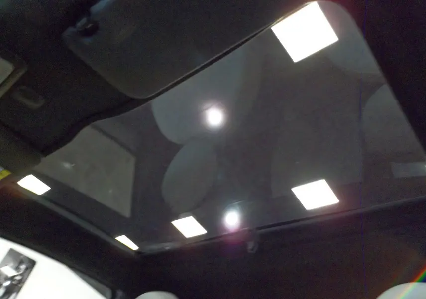 Toit panoramique en verre de la FIAT 500 Electroclash Grey, vue intérieure vers le ciel avec reflets lumineux.