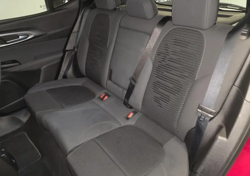 Vue intérieure de la banquette arrière noire de l'Alfa Romeo Tonale 2025, avec ceinture de sécurité et porte rouge partiellement visible.