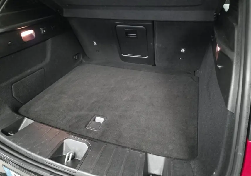 Coffre ouvert de l'Alfa Romeo Tonale rouge 2025, vue intérieure montrant le tapis de sol noir et les rangements.