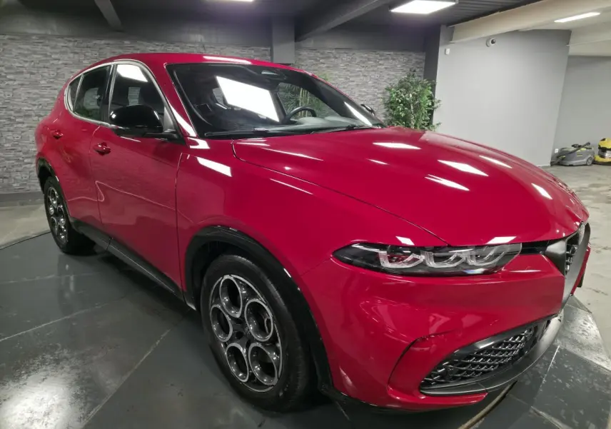 Alfa Romeo Tonale rouge vue 3/4 avant droit, avec jantes alliage 18 pouces et calandre caractéristique Scudetto noire.