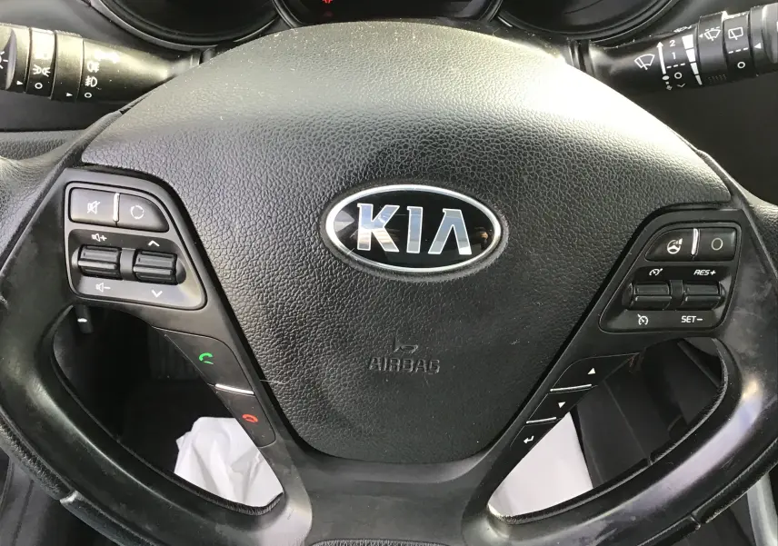 Gros plan sur le volant noir de la Kia CEE'D SW 2017, avec commandes audio et régulateur de vitesse intégrés.