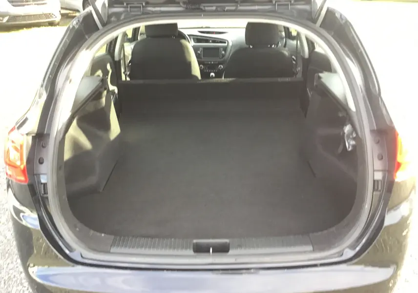 Coffre ouvert d'une KIA CEE'D SW noire 2017, vue arrière montrant l'espace de chargement et l'intérieur des sièges avant.