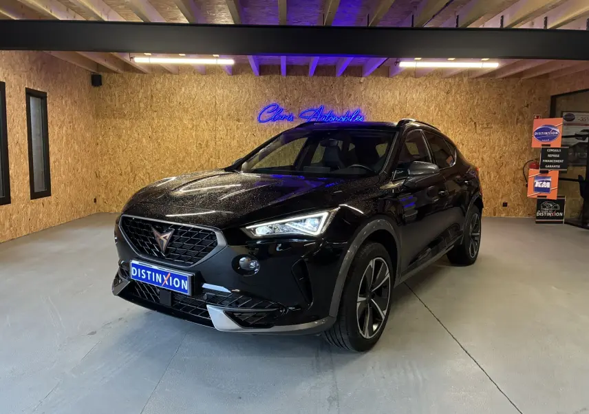 Vue 3/4 avant d’un CUPRA Formentor noir brillant avec phares allumés dans un showroom au sol gris.