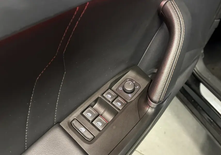 Gros plan sur la commande des vitres et rétroviseurs côté gauche en cuir noir avec surpiqûres contrastantes dans une CUPRA Formentor noire 2023.