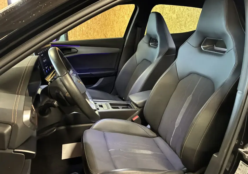 Vue intérieure côté conducteur de la CUPRA Formentor noire 2023, sièges sport en cuir et tissu avec surpiqûres contrastées.