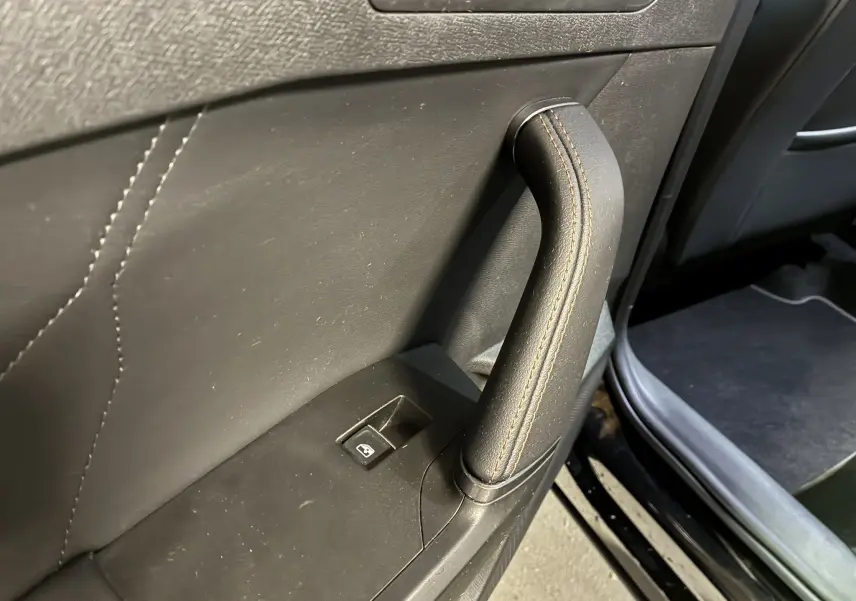 Poignée de porte intérieure en cuir noir avec surpiqûres marron sur la porte côté gauche d'une CUPRA Formentor 2023.