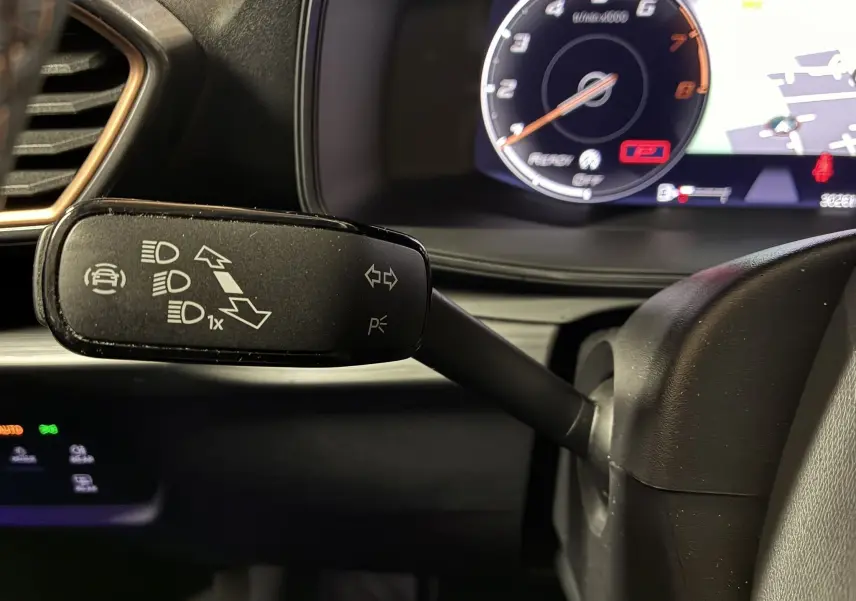 Gros plan sur le commodo gauche noir du tableau de bord du CUPRA Formentor 1.4 E-HYBRID 2023 avec compteur numérique en arrière-plan.