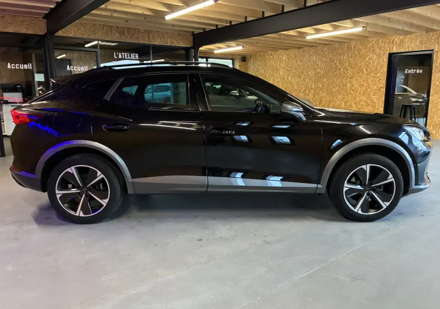Vue de profil côté gauche d’un CUPRA Formentor noir 2023 hybride rechargeable, avec jantes alliage et détails gris sur les passages de roues.
