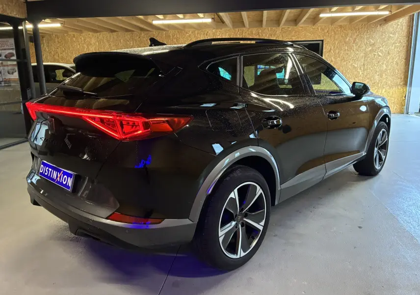 Vue 3/4 arrière droite d’un CUPRA Formentor noir 2023 avec feux arrière allumés et jantes alliage distinctives.