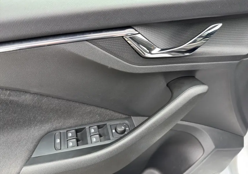 Gros plan sur la porte avant gauche du Skoda Kamiq 2023, montrant les commandes électriques des vitres et le design noir mat.