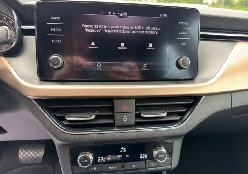 Vue rapprochée de l'écran tactile central et de la console de climatisation du Skoda Kamiq 2023, intérieur noir avec insert bois clair.