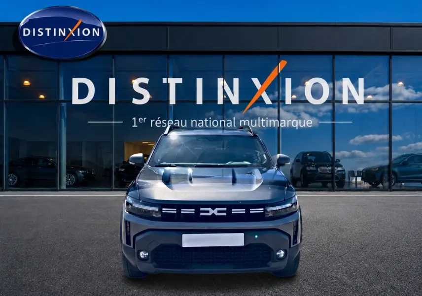 Vue frontale du Dacia Duster 1.2 mild hybrid 140 Journey gris schiste, avec calandre distinctive et phares LED allumés.