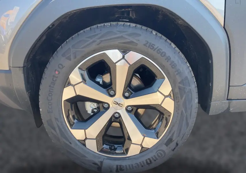 Gros plan sur la roue avant droite du Dacia Duster gris schiste avec jante alliage 18 pouces au design géométrique.