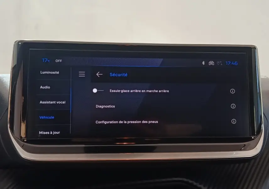Écran tactile central de la Peugeot 208 Hybrid gris clair affichant le menu sécurité avec options essuie-glace et diagnostics.