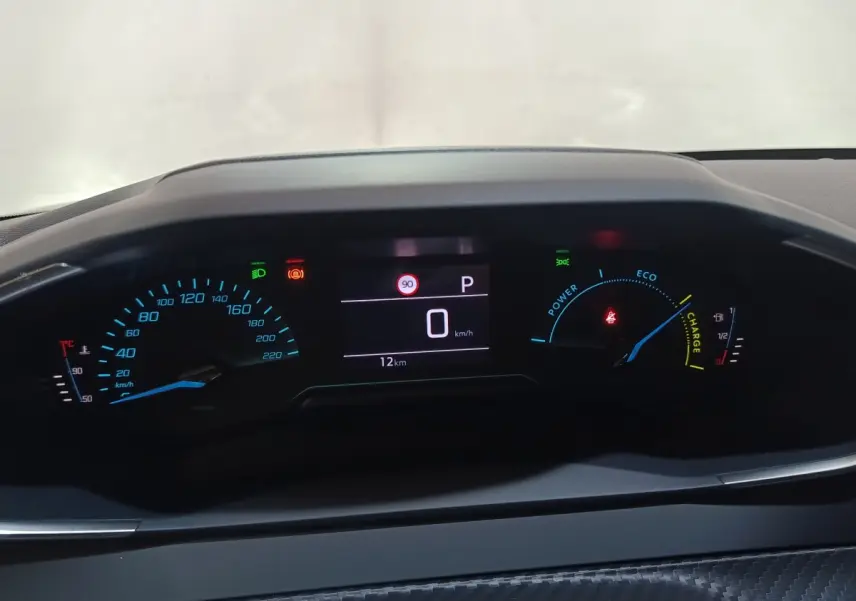 Vue rapprochée du combiné d'instruments numérique de la Peugeot 208 Hybrid 2025, affichage vitesse et indicateurs hybrides.